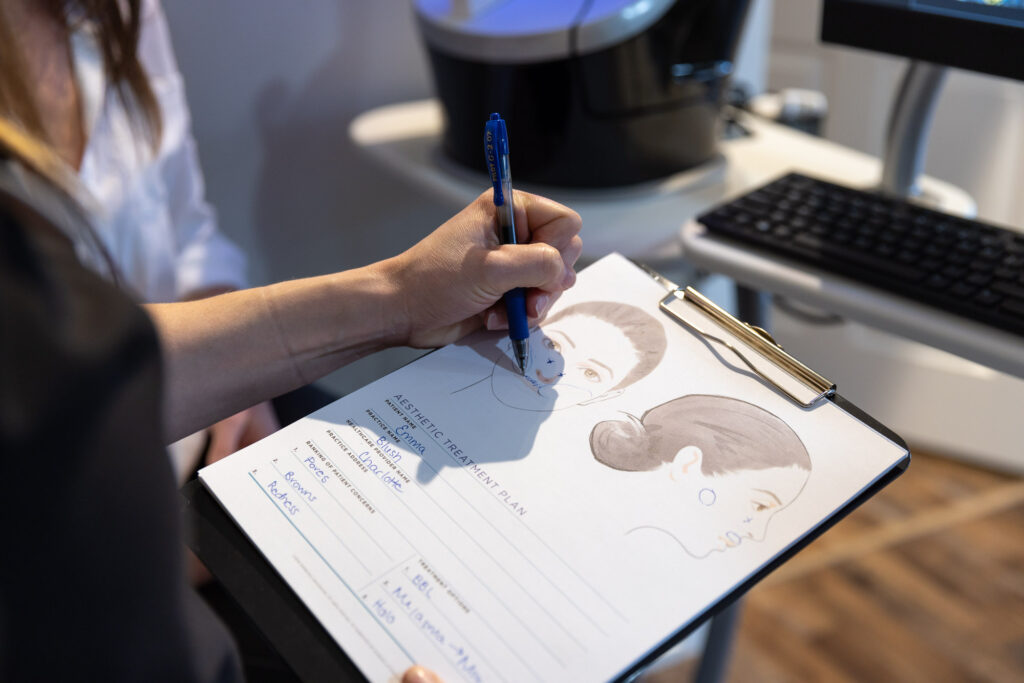 A professional reviews a patient's needs while looking at a clipboard to determine her best anti-aging treatments in Toledo