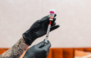 A provider wearing black gloves uses a syringe to prepare Sculptra collagen stimulating injections in Columbus and Toledo