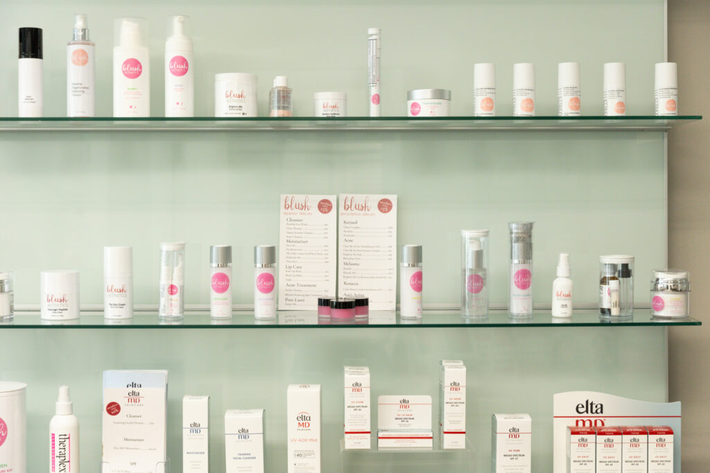 Wide shot of medical-grade skincare arranged on shelves in front of a green wall, including an at-home rosacea treatment in Toledo