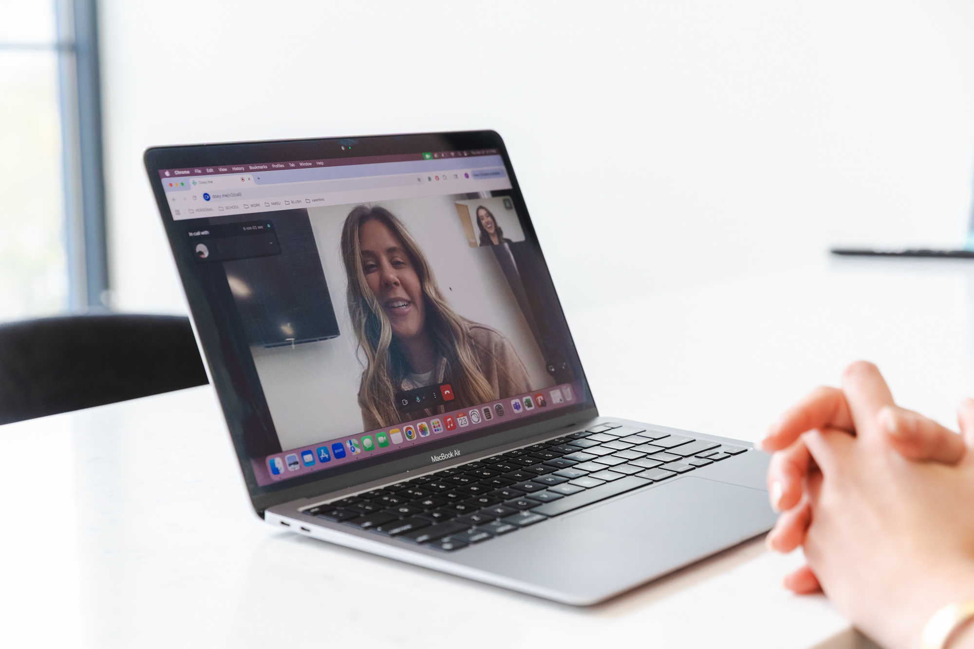 A laptop on a table showing a woman over video chat.