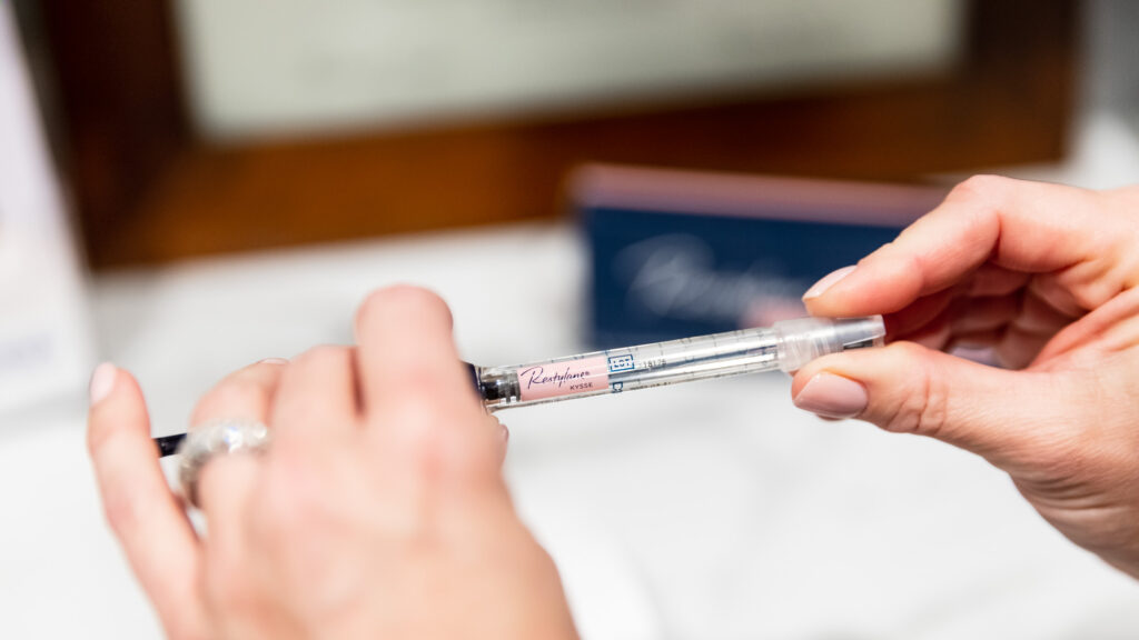 A Blush Aesthetics injector holds a vial of Restylane, a type of HA dermal filler used for natural lip injections in Columbus.