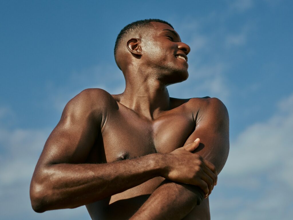 A shirtless man, with minimal hair on his arms and chest, standing in the sun after laser hair removal for men in Columbus.
